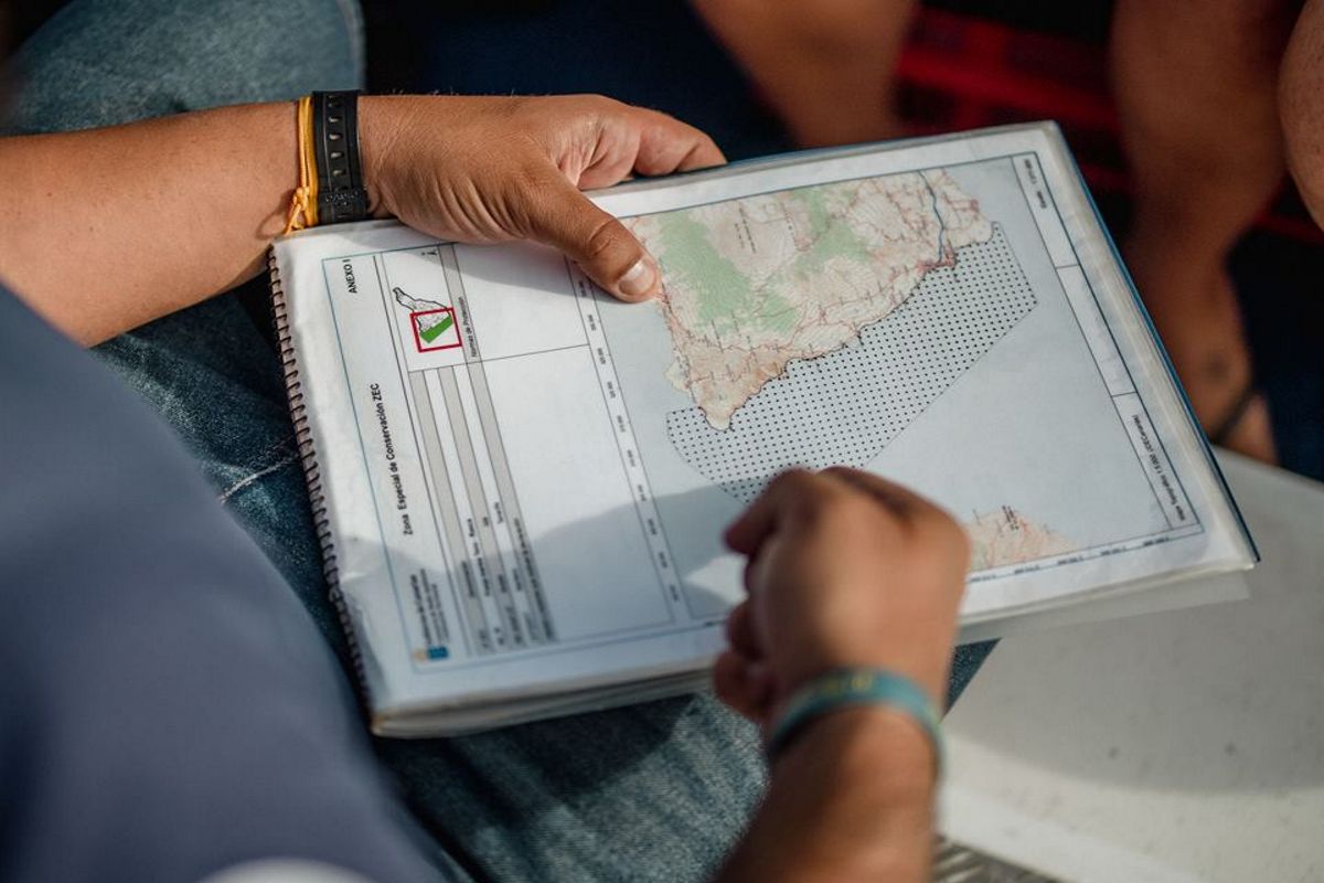 Persona sosteniendo un mapa de Tenerife en un cuaderno espiral.