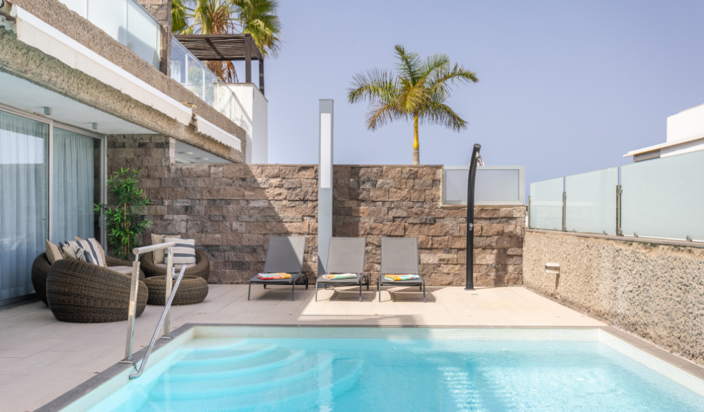 Piscina al aire libre con sillas y palmera en un hotel de Tenerife.