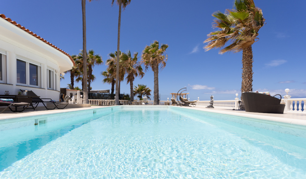 Piscina al aire libre con palmeras en Tenerife bajo un cielo despejado.