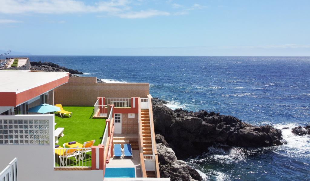 Terraza con césped y tumbonas junto al mar en un acantilado en Tenerife.