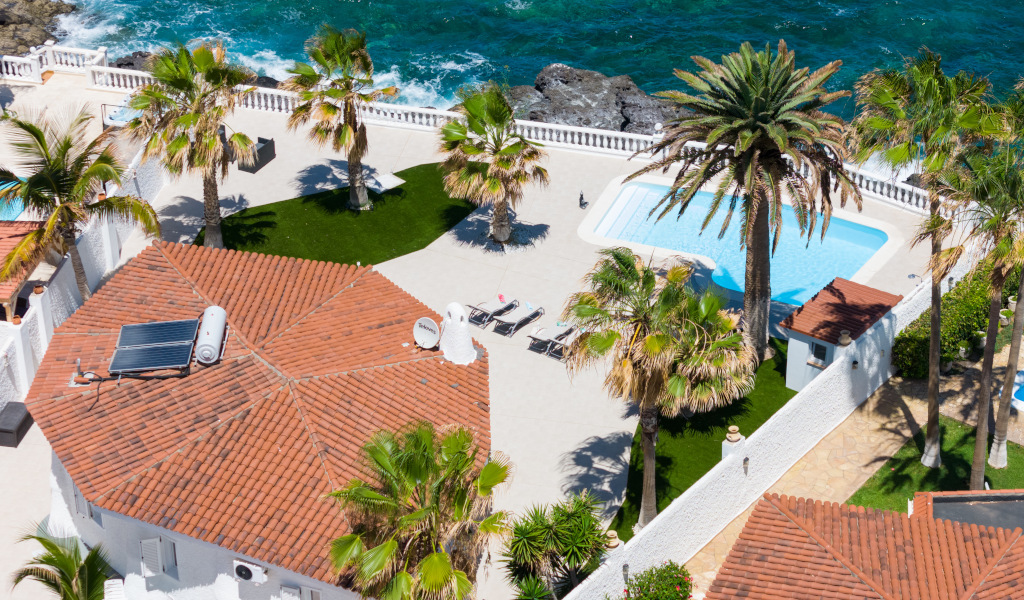 Vista aérea de terraza con piscina, palmeras y mar en Tenerife.