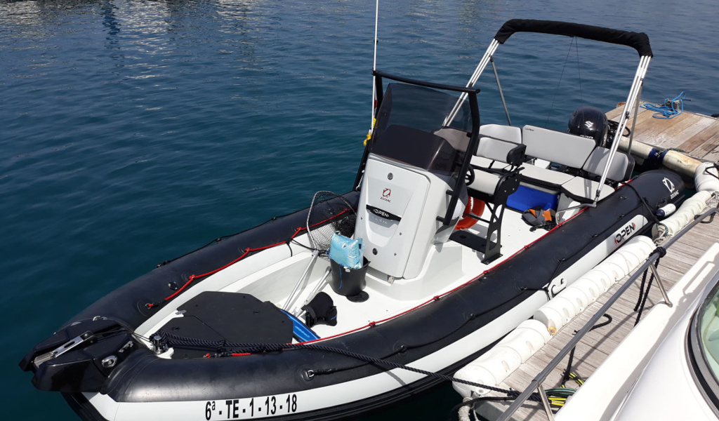 Lancha neumática atracada en puerto de Tenerife, con asientos y motor visible.