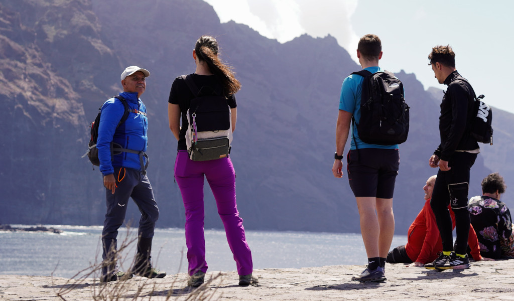 Grupo de personas con mochilas frente a acantilados en Tenerife.
