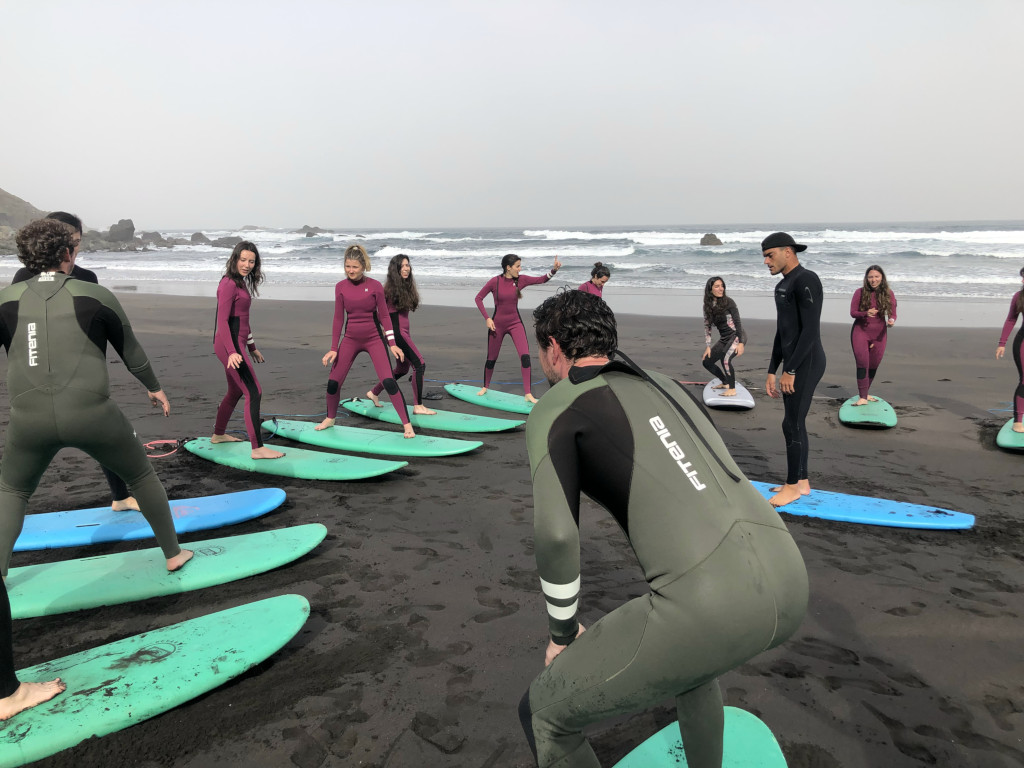 Grupo de personas aprendiendo a surfear en la playa de Tenerife.