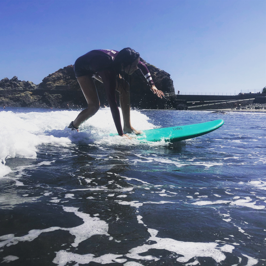 Surfista en tabla verde sobre ola en la costa de Garachico, Tenerife.