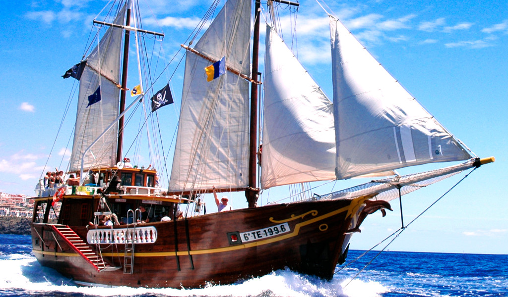 Barco de vela navegando frente a la costa de Tenerife en un día soleado.
