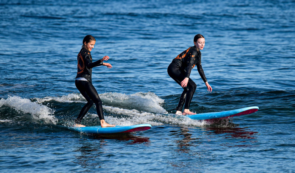 Dos personas en trajes de neopreno surfean pequeñas olas en el mar de Tenerife.
