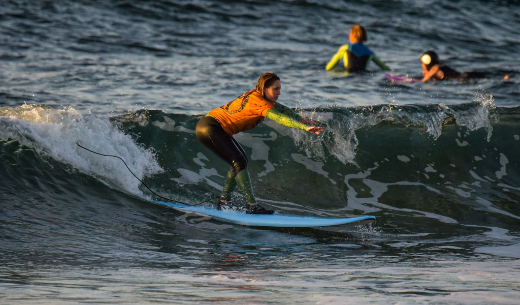 Surfista en la playa de Tenerife montando una ola al atardecer.