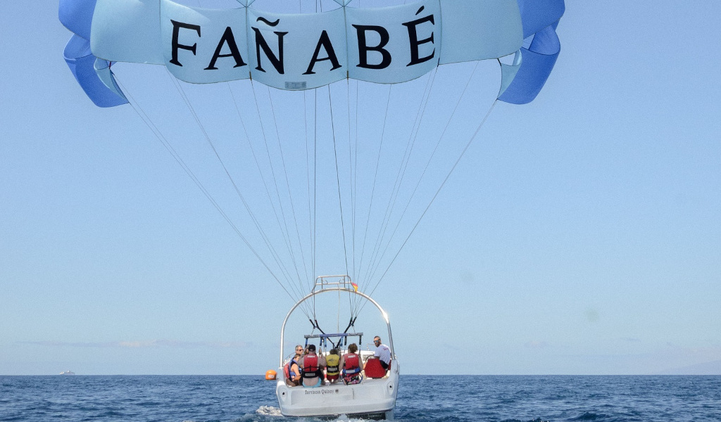 Personas practicando parasailing en Fañabé, Tenerife, sobre el mar.