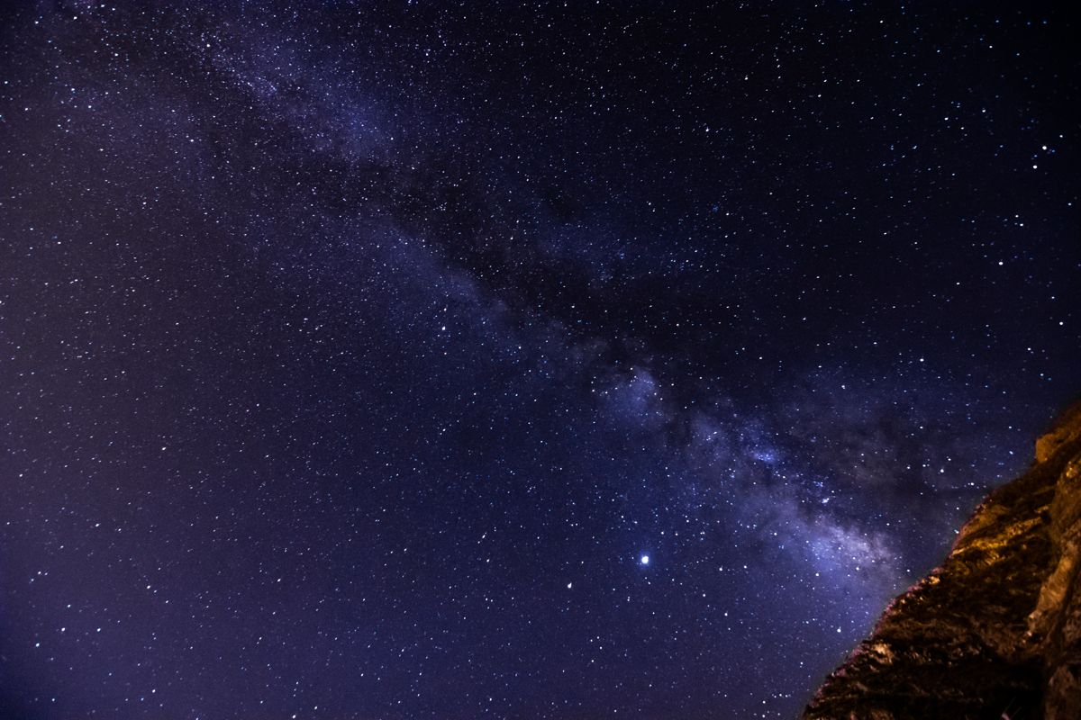 Cielo estrellado con la Vía Láctea visible sobre un paisaje rocoso en Tenerife.