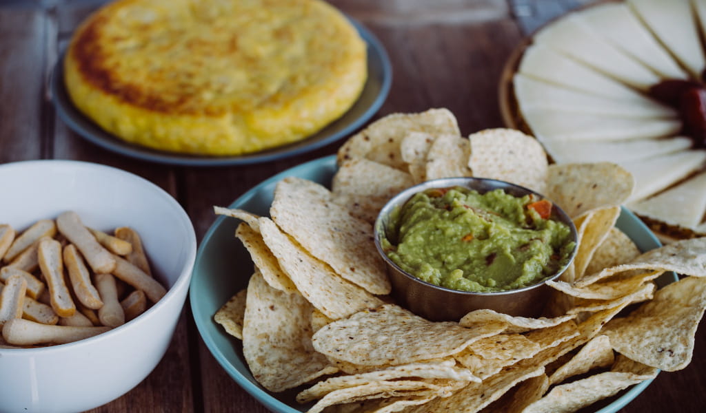 Nachos con guacamole, palitos de pan, tortilla y queso en una mesa en Tenerife.
