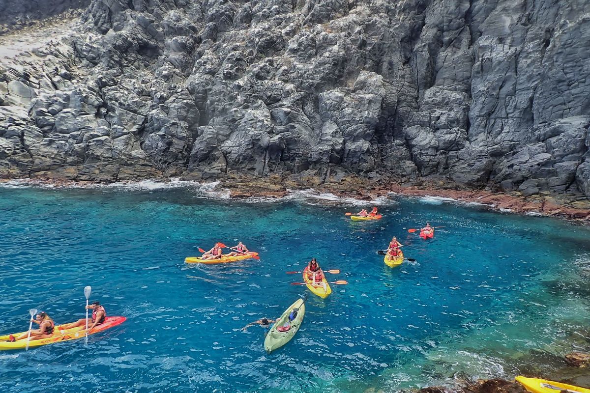 Kayaks en el agua cristalina junto a acantilados en Tenerife.