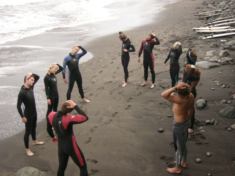 Grupo de surfistas haciendo estiramientos en la playa en Tenerife.