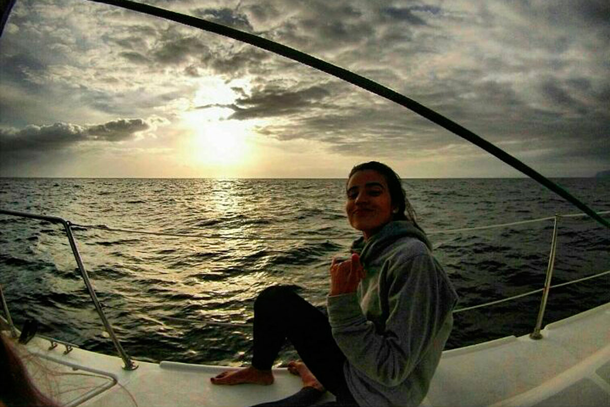 Persona sentada en un barco al atardecer cerca de la costa de Tenerife.