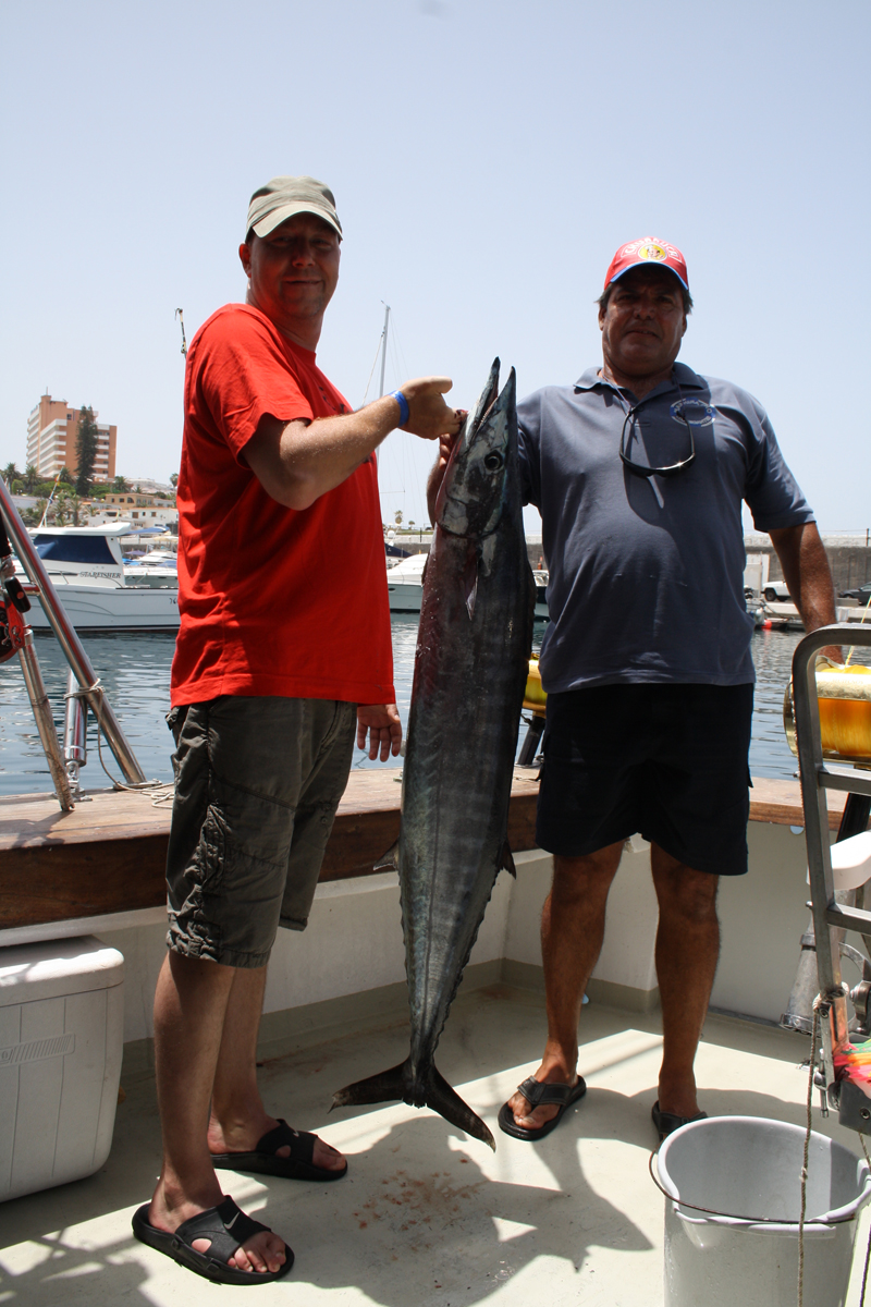 Dos personas en un barco sosteniendo un gran pez en Los Cristianos, Tenerife.