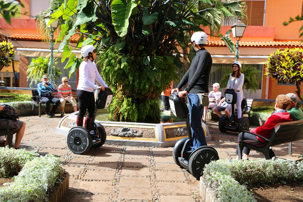 Personas en segways alrededor de una fuente en una plaza de Tenerife.