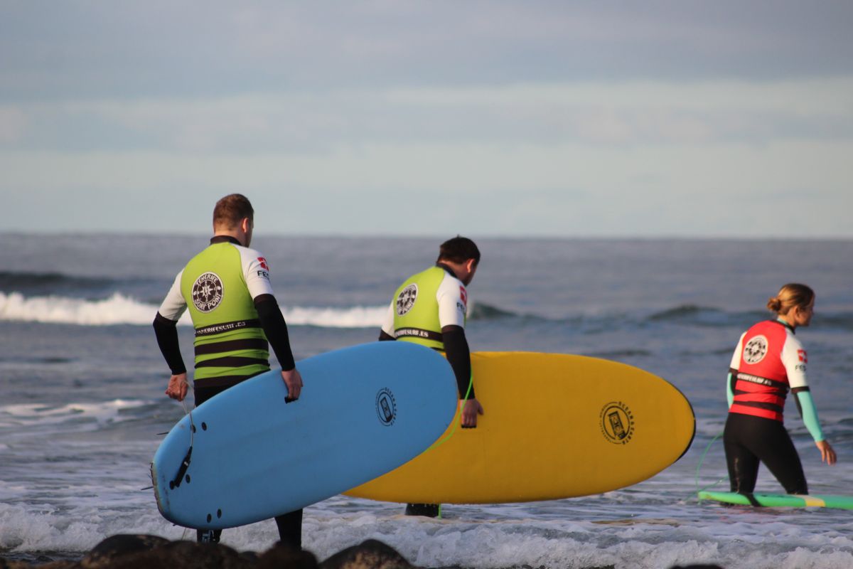 Surfistas entrando al mar con tablas coloridas en Tenerife.