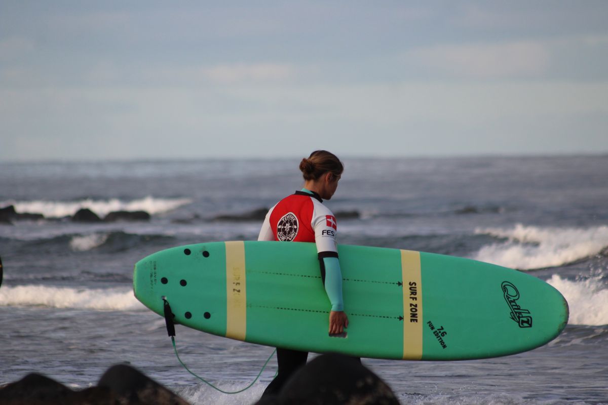 persona con tabla de surf verde en la playa de Tenerife