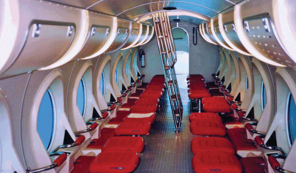 Interior de un submarino turístico en Tenerife con asientos rojos y ventanales.