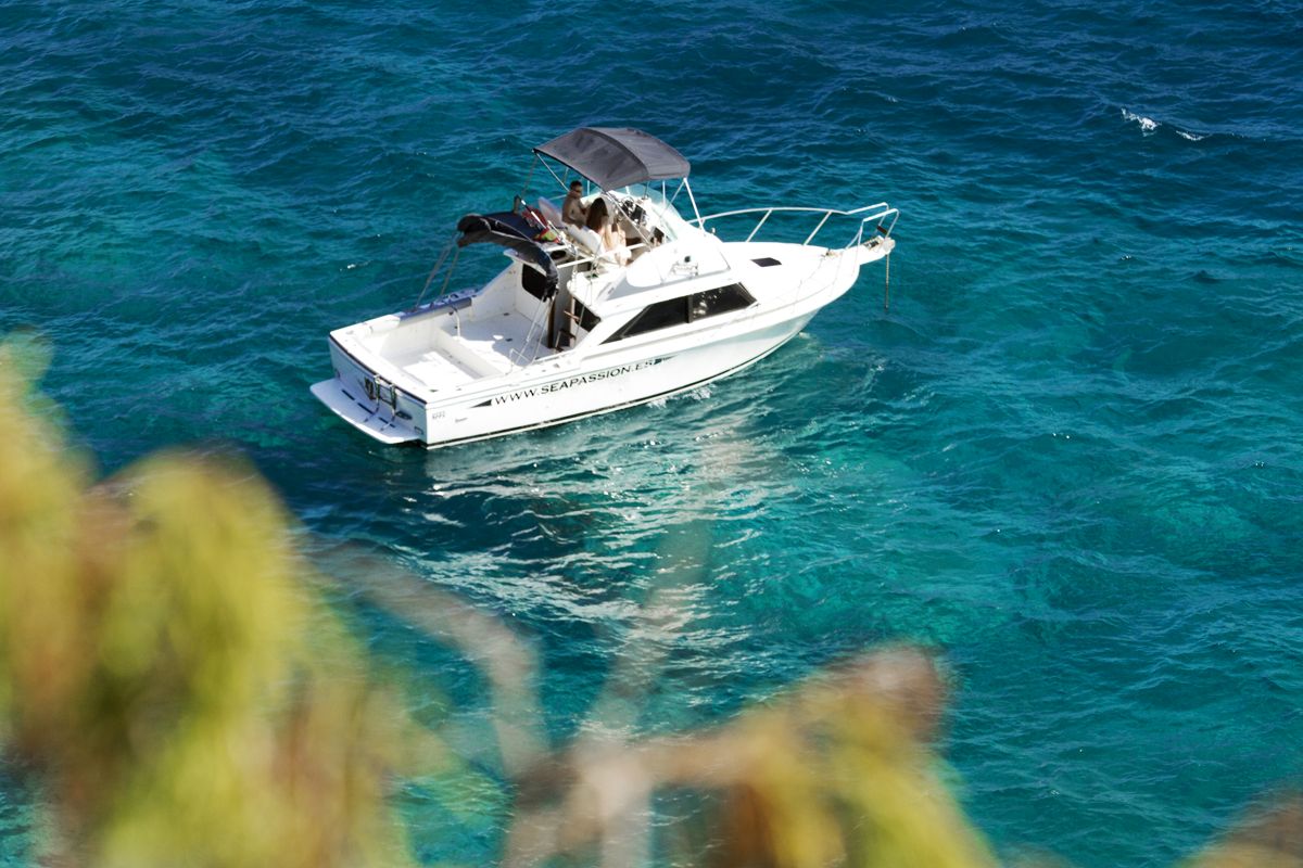 Barco navegando en las aguas azules de Tenerife con personas a bordo.