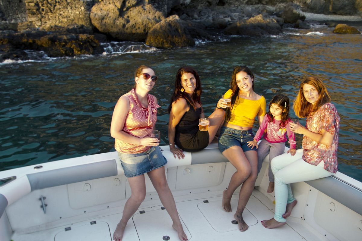 Grupo de personas en barco junto a la costa de Tenerife, disfrutando del atardecer.