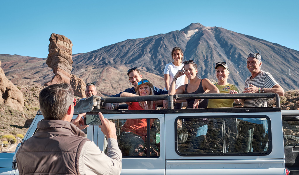 Grupo de personas en un jeep frente al Teide en Tenerife.