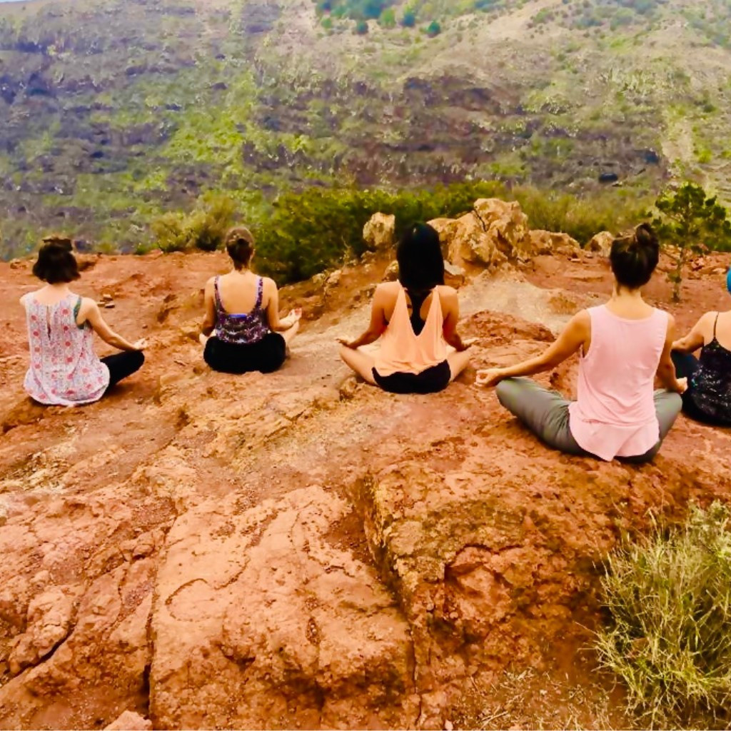 Personas meditando al aire libre en un acantilado en Tenerife.