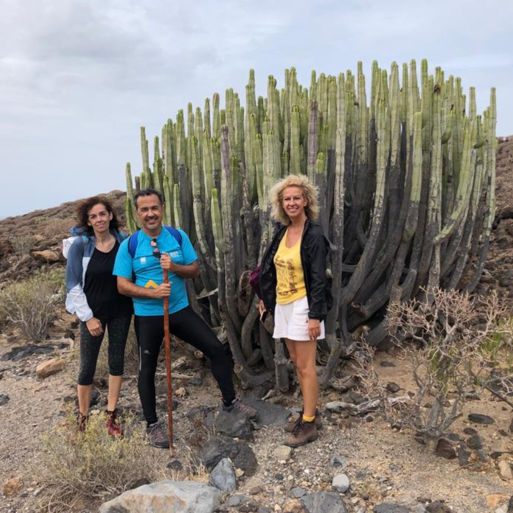 Tres personas junto a un cactus grande en un entorno rocoso en Tenerife.