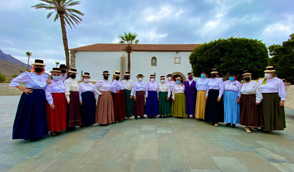 Grupo de personas con trajes tradicionales en La Gomera, Tenerife, frente a un edificio.