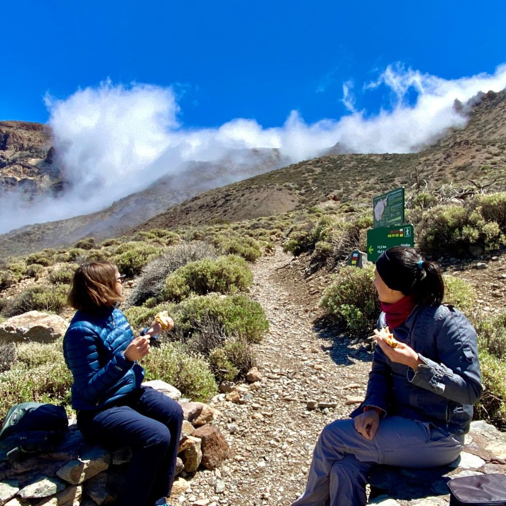 Personas sentadas comiendo en un sendero en el Parque Nacional del Teide, Tenerife.