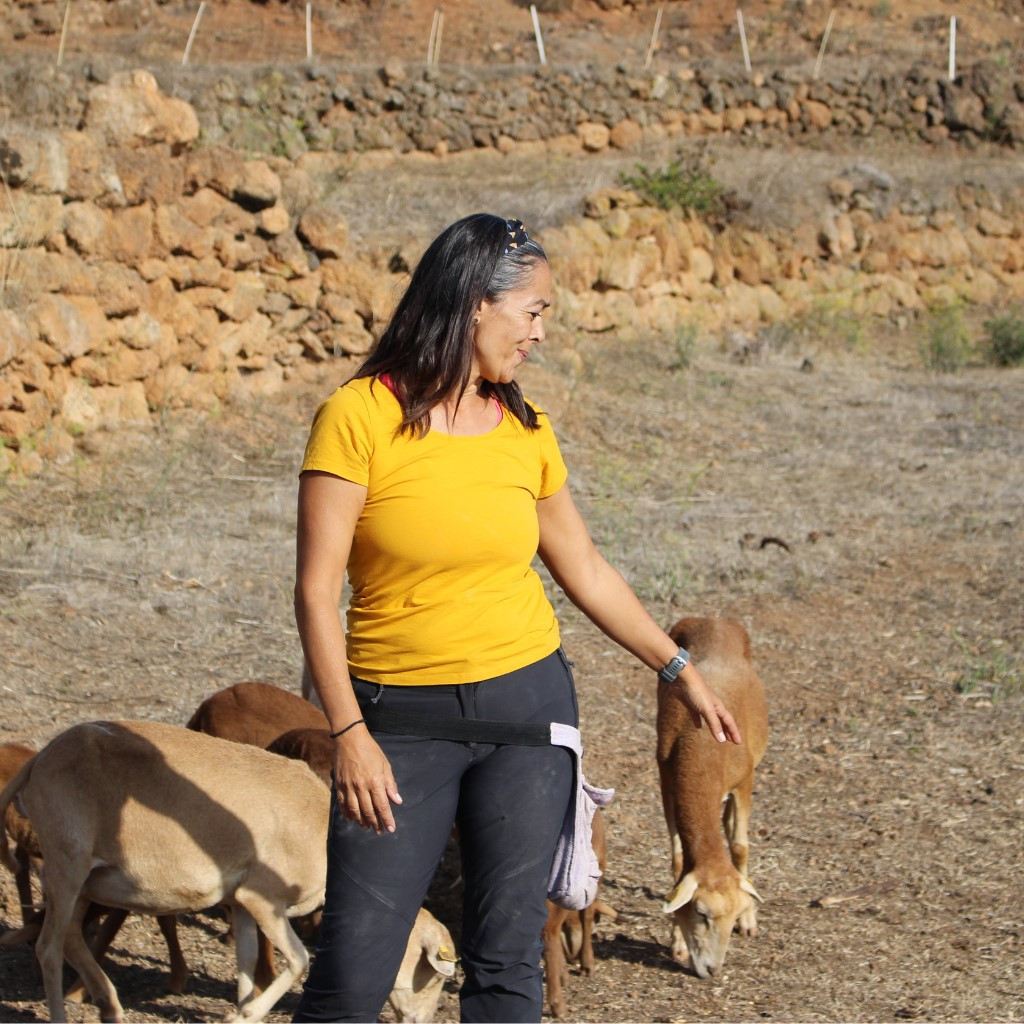 Mujer junto a cabras pastando en un terreno rural en Tenerife.