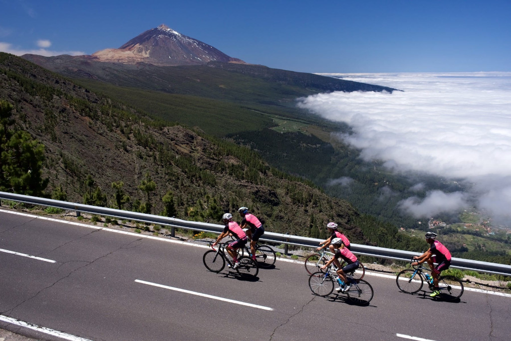 Ciclistas subiendo cerca del Teide en Tenerife con vistas al valle y al mar de nubes.