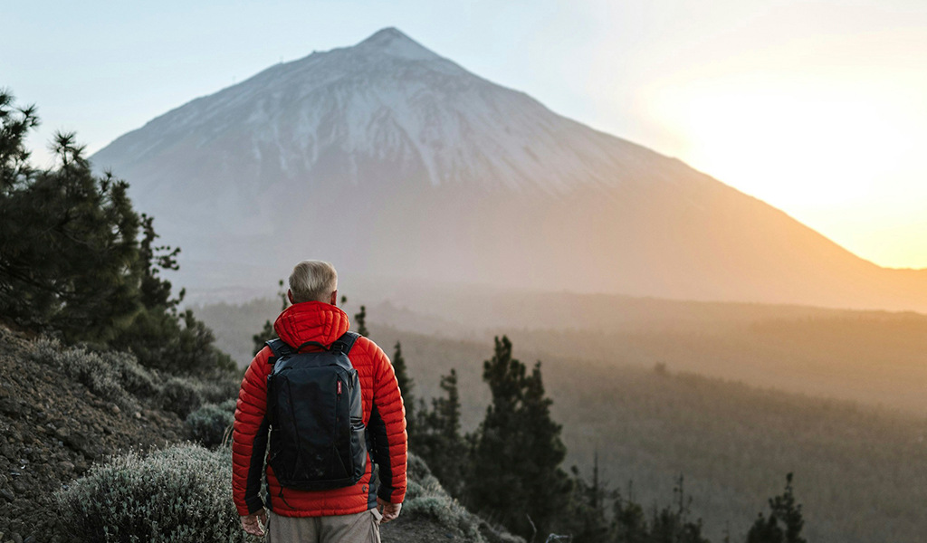 Persona con mochila contempla el amanecer en el Teide, Tenerife.