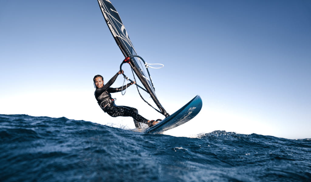 Persona practicando windsurf en el mar cerca de Tenerife bajo un cielo despejado.