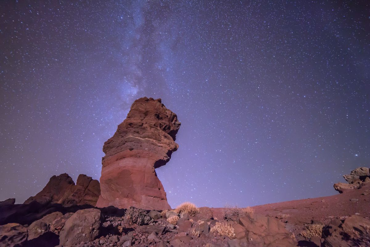Cielo estrellado sobre el Teide en Tenerife con formación rocosa prominente.