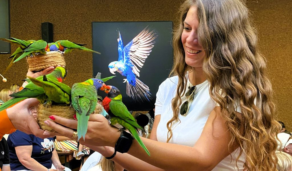 Mujer sosteniendo varios loros en el Loro Parque de Tenerife.