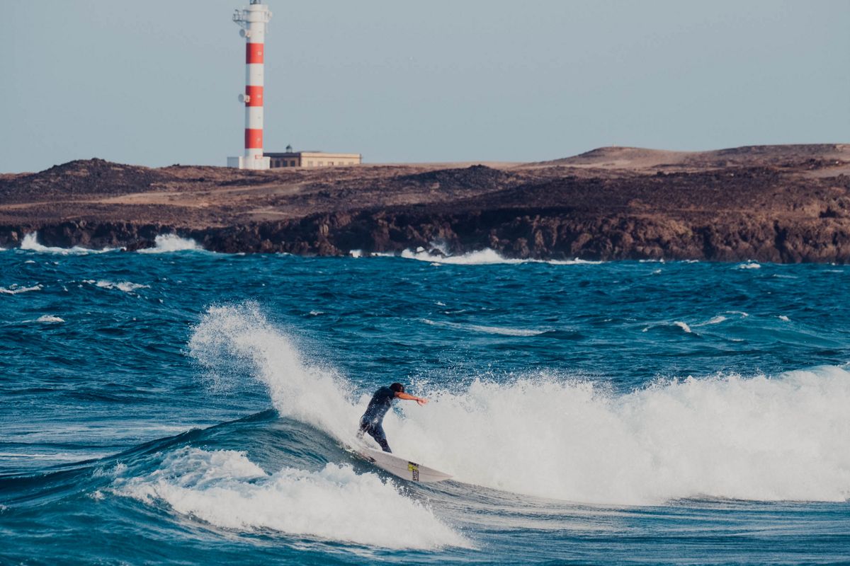 Surfero montando una ola frente al faro en Punta de Hidalgo, Tenerife.