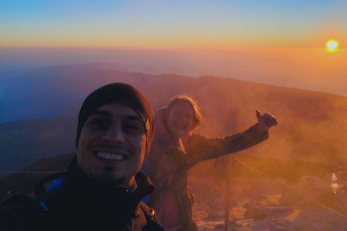 Personas sonrientes al amanecer en el Teide, Tenerife, con el sol de fondo.