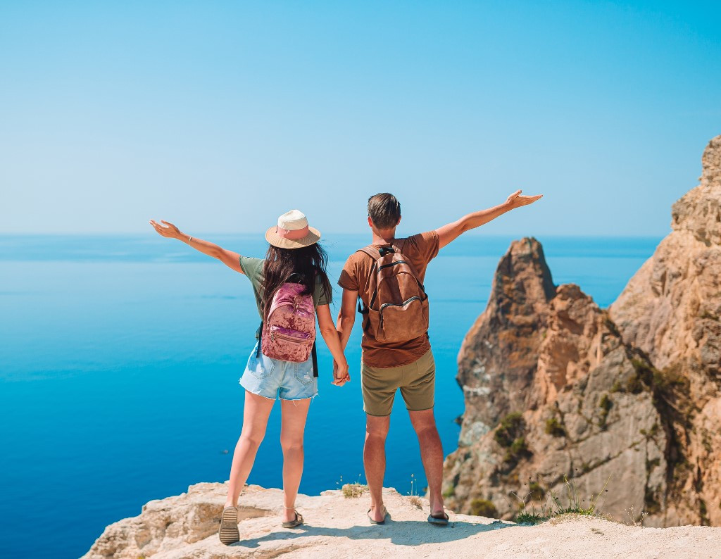 Pareja con mochilas disfrutando vista del mar desde un acantilado en Tenerife.