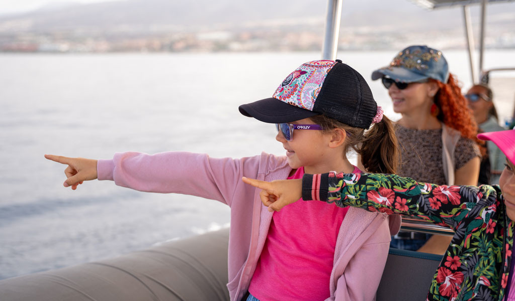 Niñas señalando desde un bote en la costa de Tenerife.