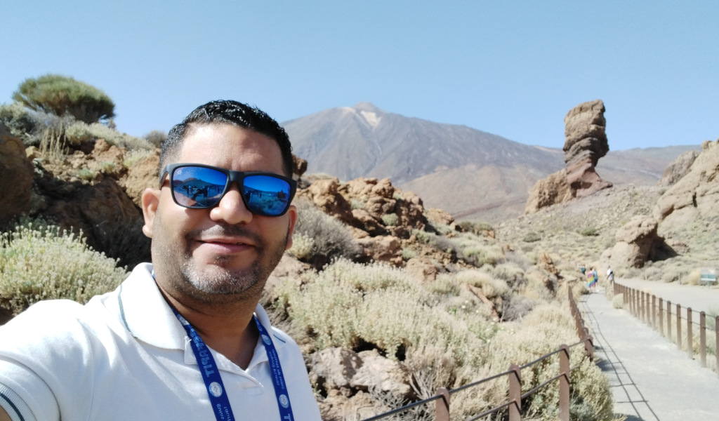 Persona con gafas de sol en el Parque Nacional del Teide, Tenerife. Montaña y formación rocosa detrás.