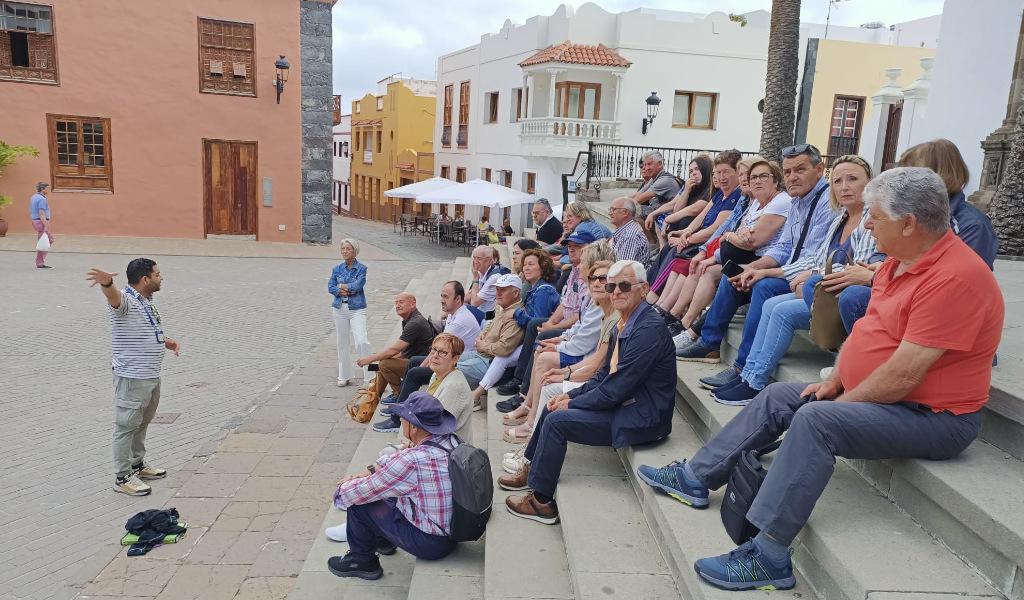 Grupo de turistas en una plaza de La Laguna, Tenerife, escuchando a un guía turístico.