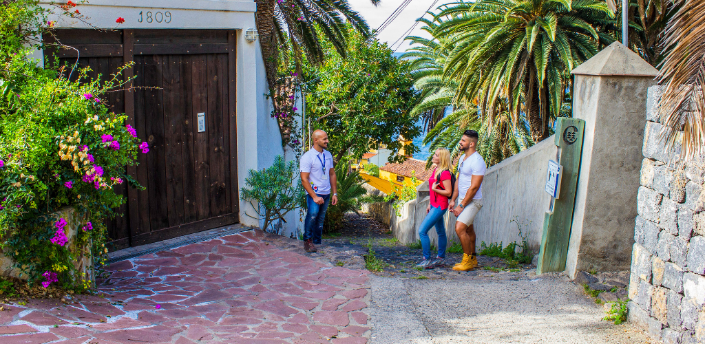 Tres personas conversando en una calle rodeada de palmeras en Tenerife.