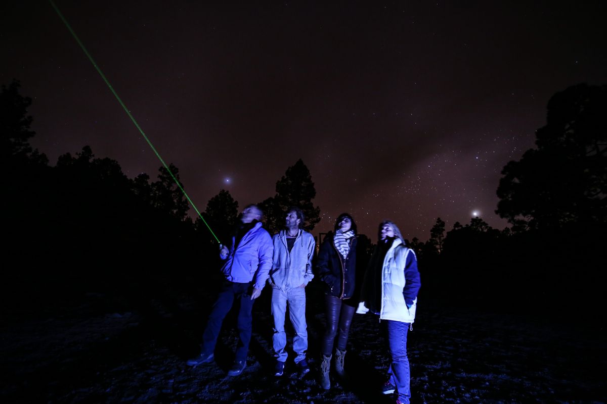 Personas observan el cielo estrellado en Tenerife, una apunta láser verde.