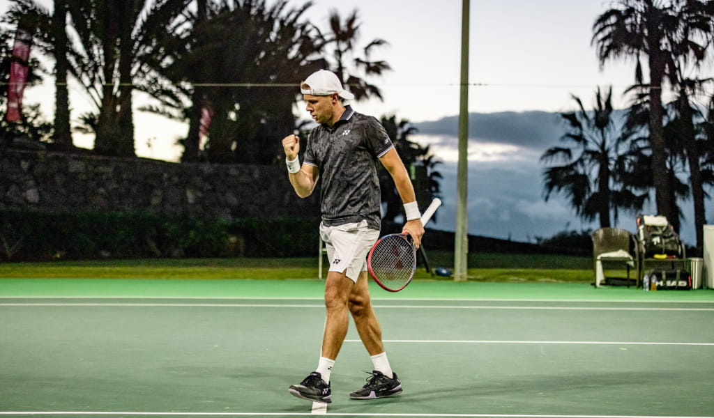 Tenista celebrando en la cancha al aire libre en Tenerife al atardecer.