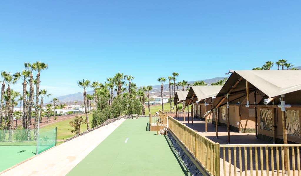 Cabañas junto a palmeras y montañas en un complejo en Tenerife.