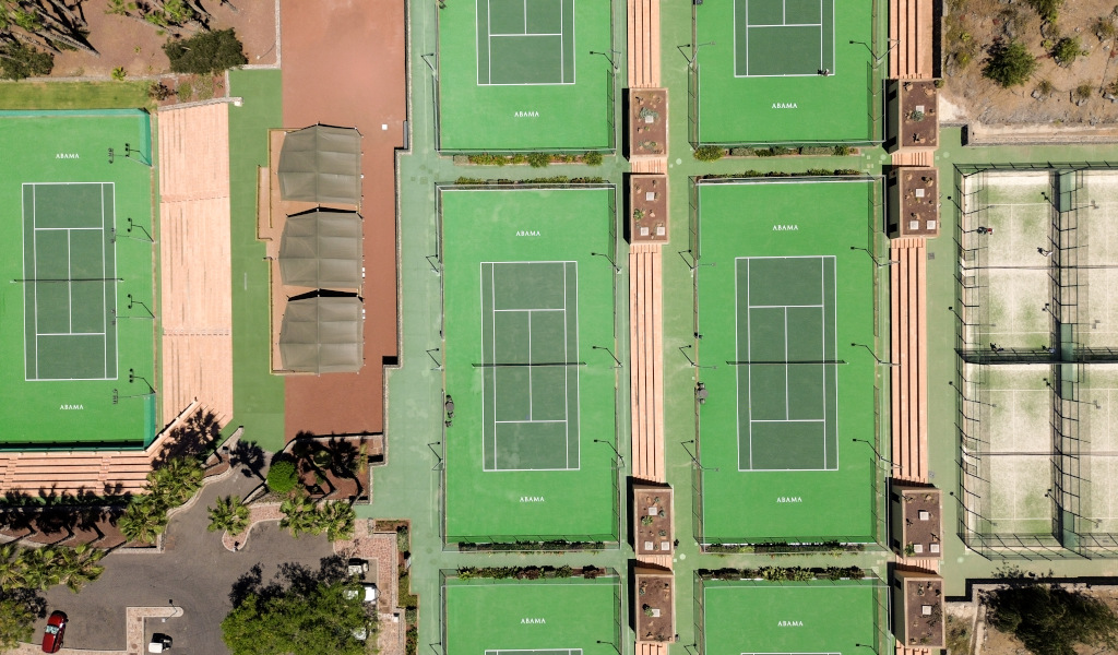 Vista aérea de canchas de tenis en Abama, Tenerife, rodeadas de vegetación y zonas de descanso.