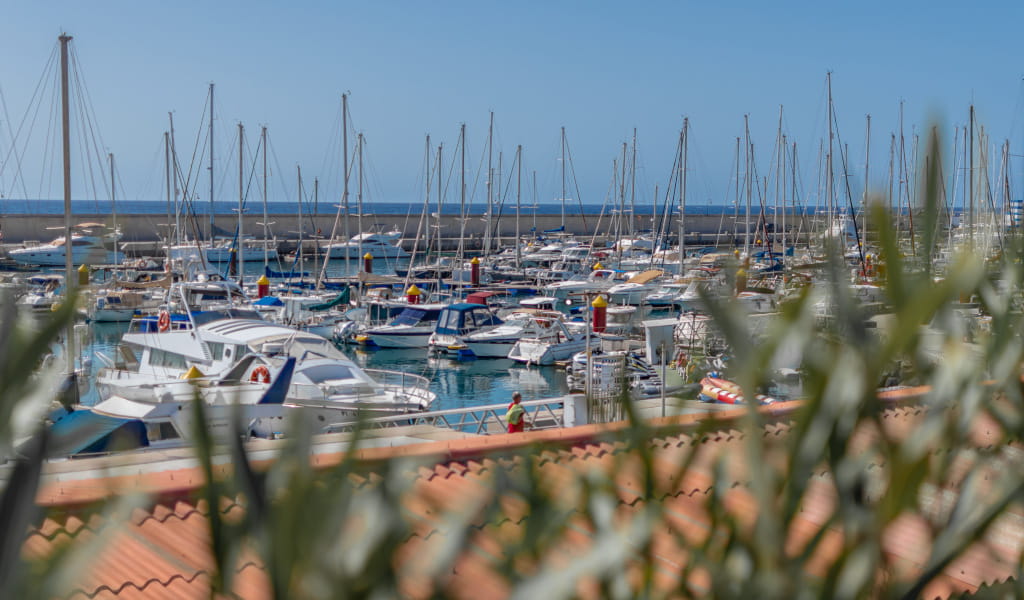 Barcos amarrados en el puerto de Los Cristianos, Tenerife, con el mar de fondo.