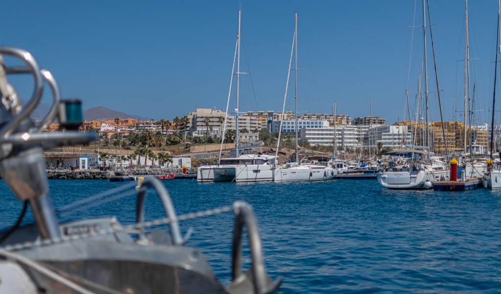 Puerto deportivo en Costa Adeje, Tenerife, con yates y edificios al fondo.