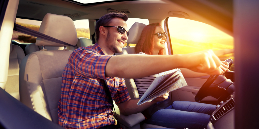 Pareja sonriente en un coche con mapa en Tenerife durante atardecer.